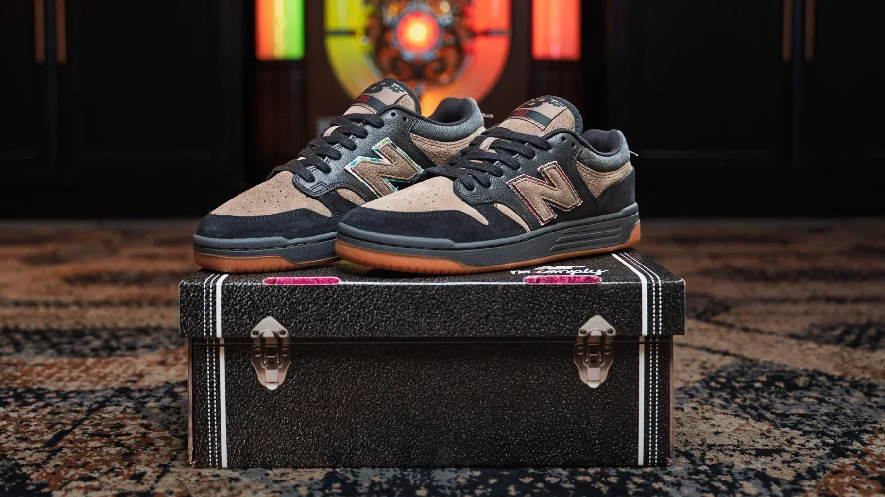 A pair of New Balance x No-Comply 'Hippies & Cowboys' NM480 in black and arid stone propped on a saddle. Available in-store on June 13, 2026 at 10am