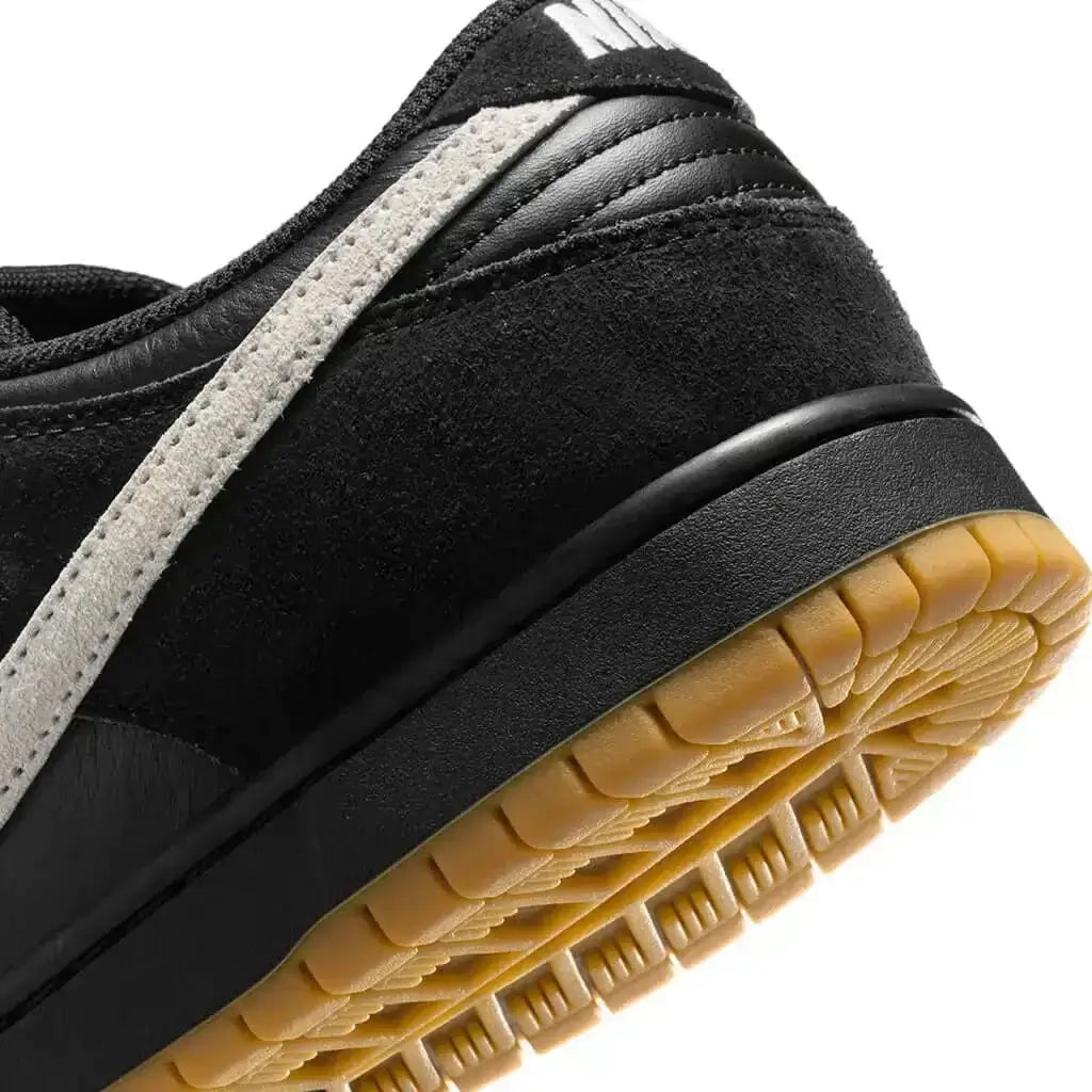 A close up of the heel of a Nike SB Dunk Low Pro shoe featuring a black and white color scheme with a tan sole on white background.