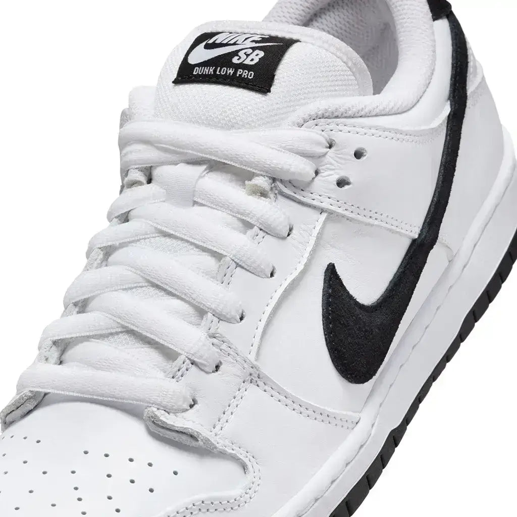 A close up of a Nike SB Dunk Low Pro shoe featuring white uppers with black accents and a black outsole on a white background.