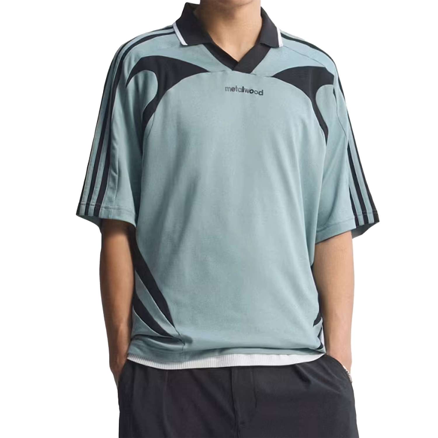 Model wearing Green Earth Adidas x Metalwood Studio golf polo with black accents on a white background