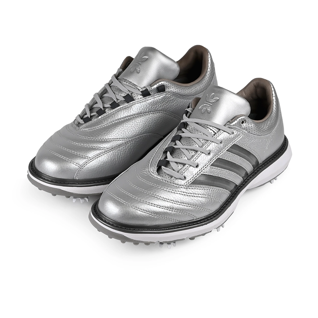 A pair of silver metallic Adidas x Metalwood MC70 golf shoes with gray stripes on a white background