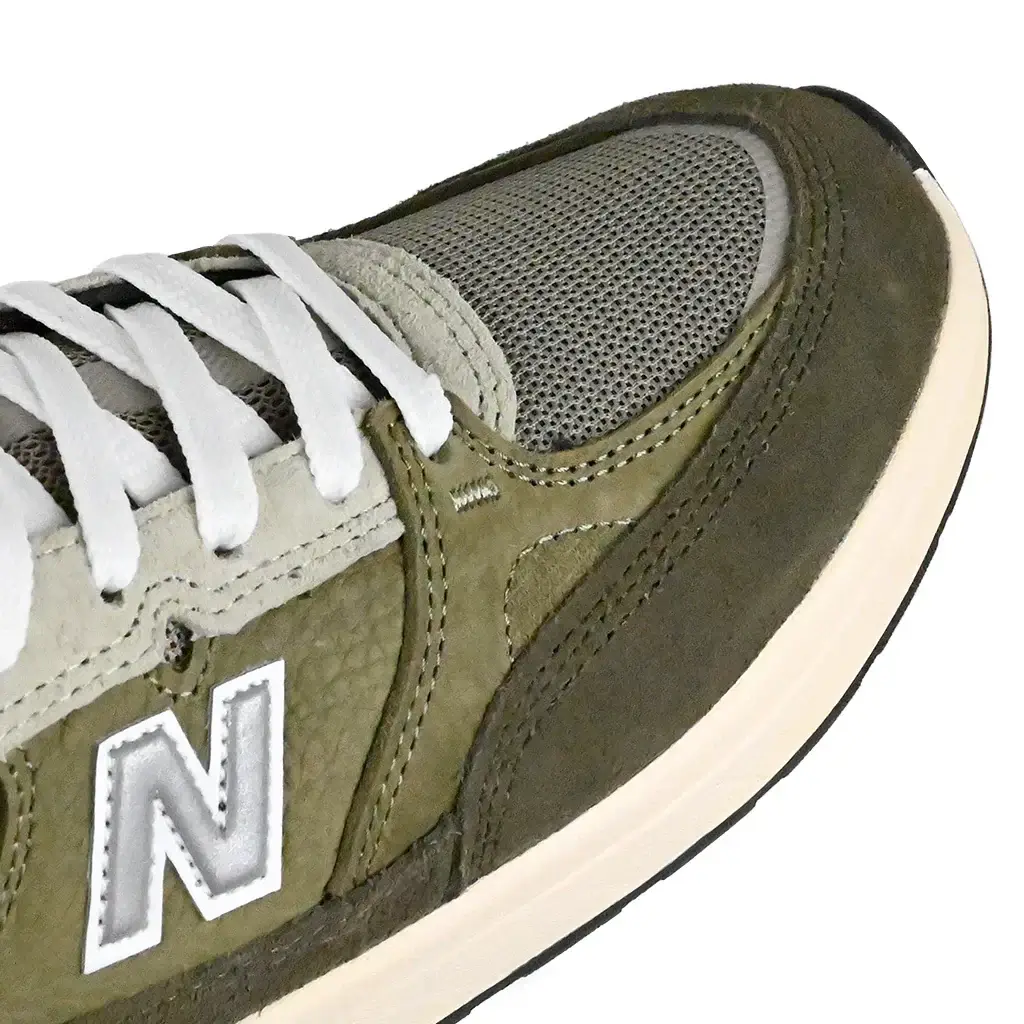 Close up of Olive NM933 sneaker with New Balance logo on a white background