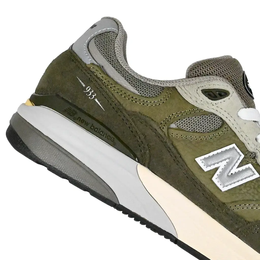 Close up of Olive NM933 sneaker with New Balance logo on a white background