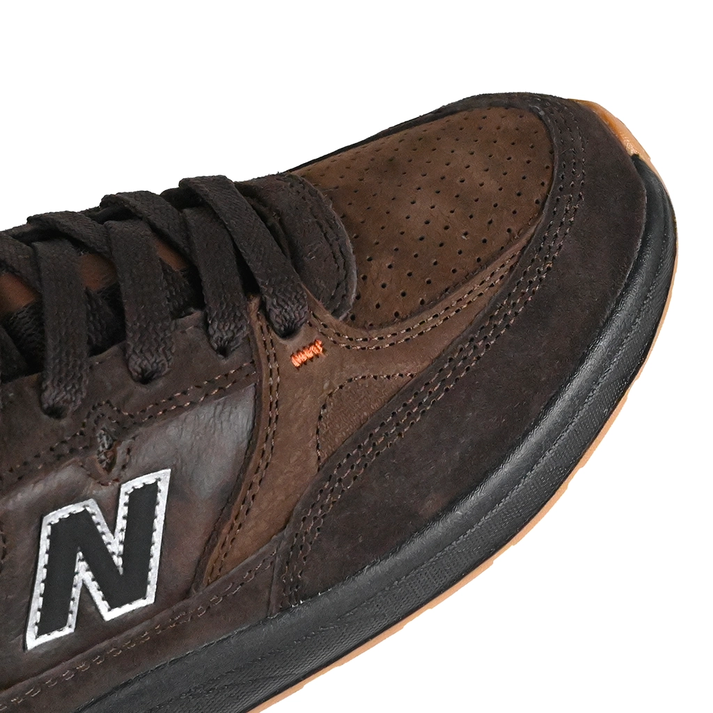 Close up of Brown NM933 sneaker with New Balance logo on a white background