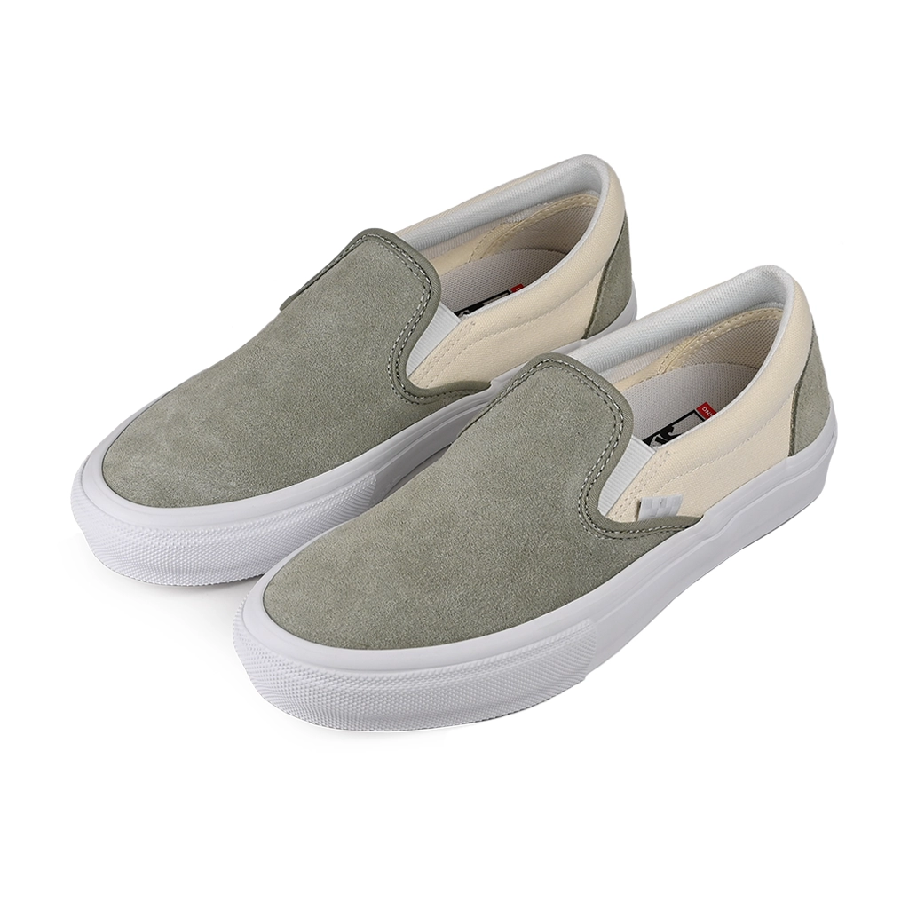 Pair of Vans Skateboarding Slip-On green sneakers with white soles on a white background
