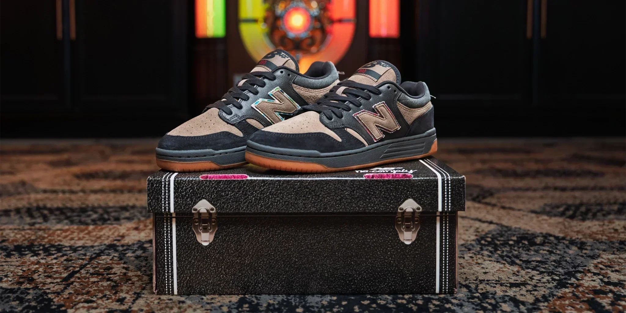 A pair of New Balance x No-Comply 'Hippies & Cowboys' NM480 in black and arid stone propped on a saddle. Available in-store on June 13, 2026 at 10am