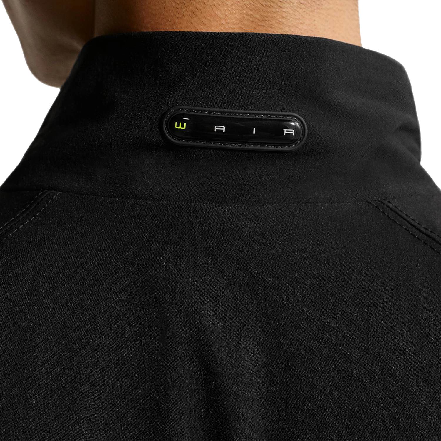 Close up of a person wearing a black Nike SB Ishod Wair track jacket with a WAIR logo on a white background