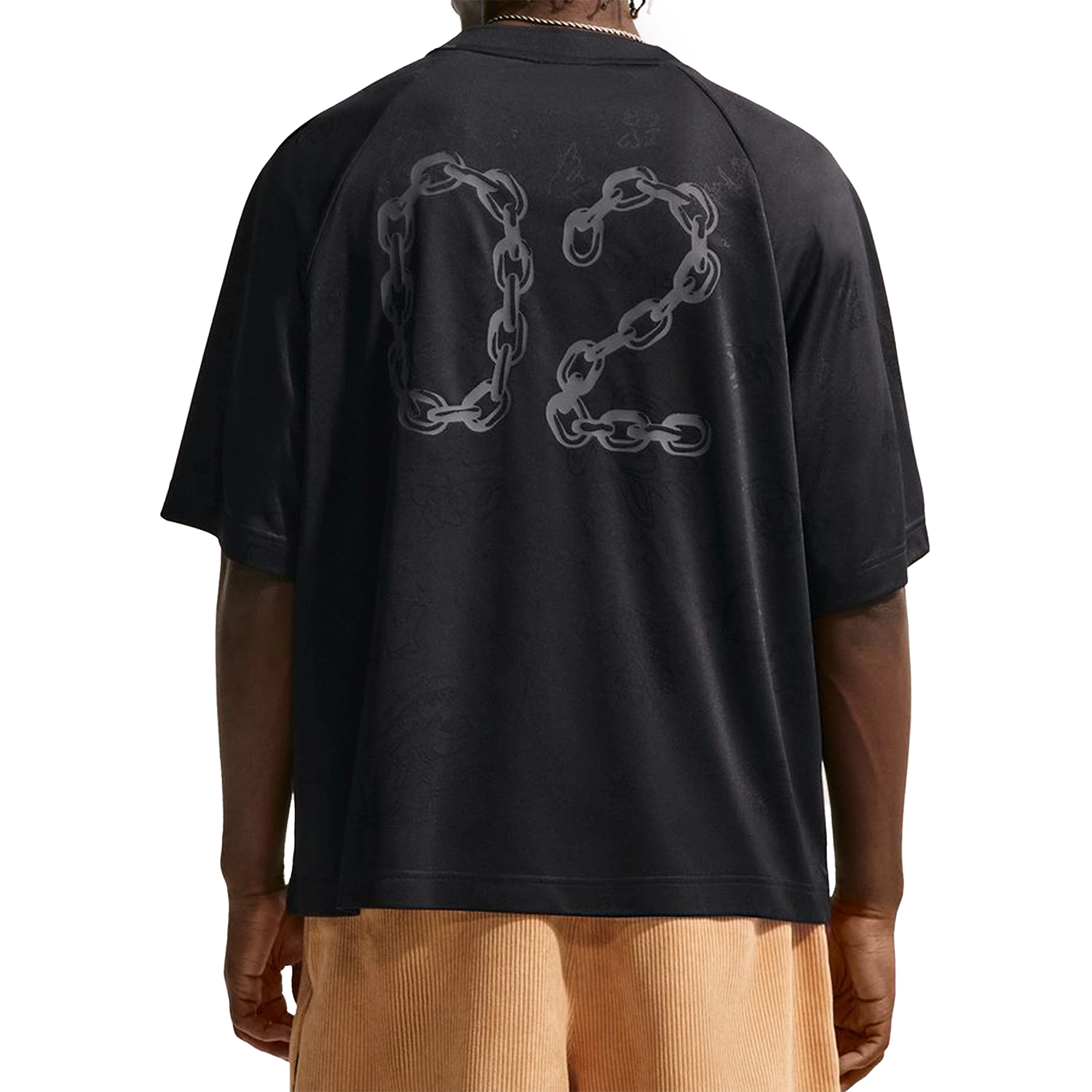 Person wearing a black Nike SB Jacquard Skate Jersey with chain graphic on a white background