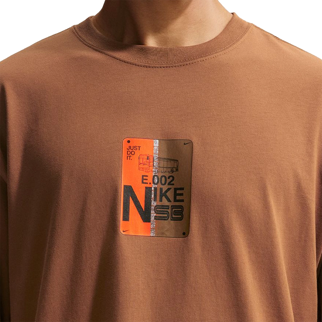 Brown Nike SB Muni-Pass t-shirt with a metallic patch featuring 'Nike SB' branding on a white background