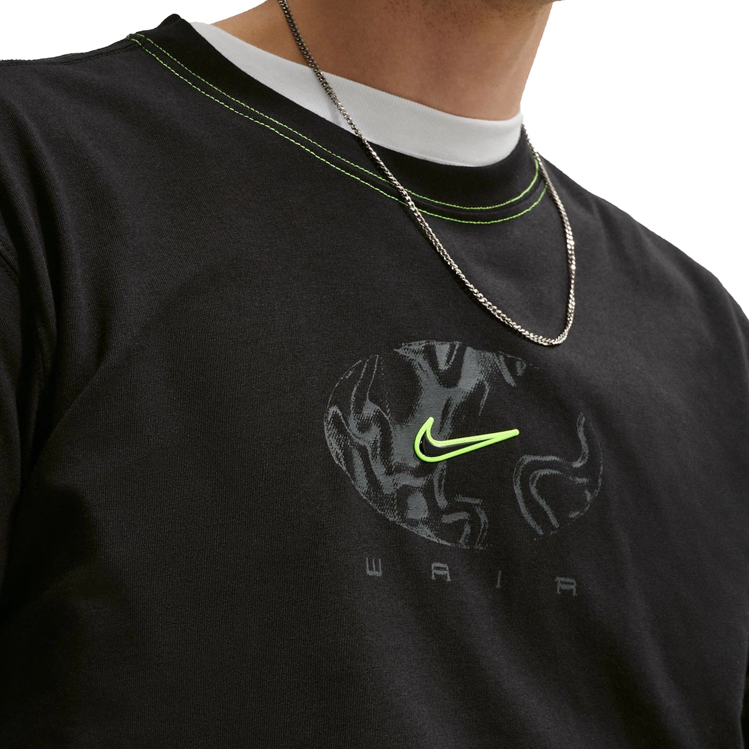 Close up of a black Nike SB Ishod Wair athletic t-shirt with a logo worn over a white long-sleeve shirt on a white background