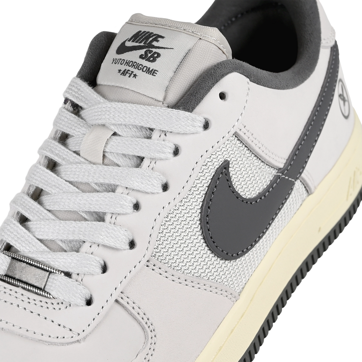 Close up of White leather and mesh Nike SB x Yuto Horigome Air Force 1 skateboard sneaker with iron grey swoosh and family crest on a white background