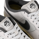 Tongue tags of White leather and mesh Nike SB x Yuto Horigome Air Force 1 skateboard sneakers with iron grey swoosh and family crest on a white background