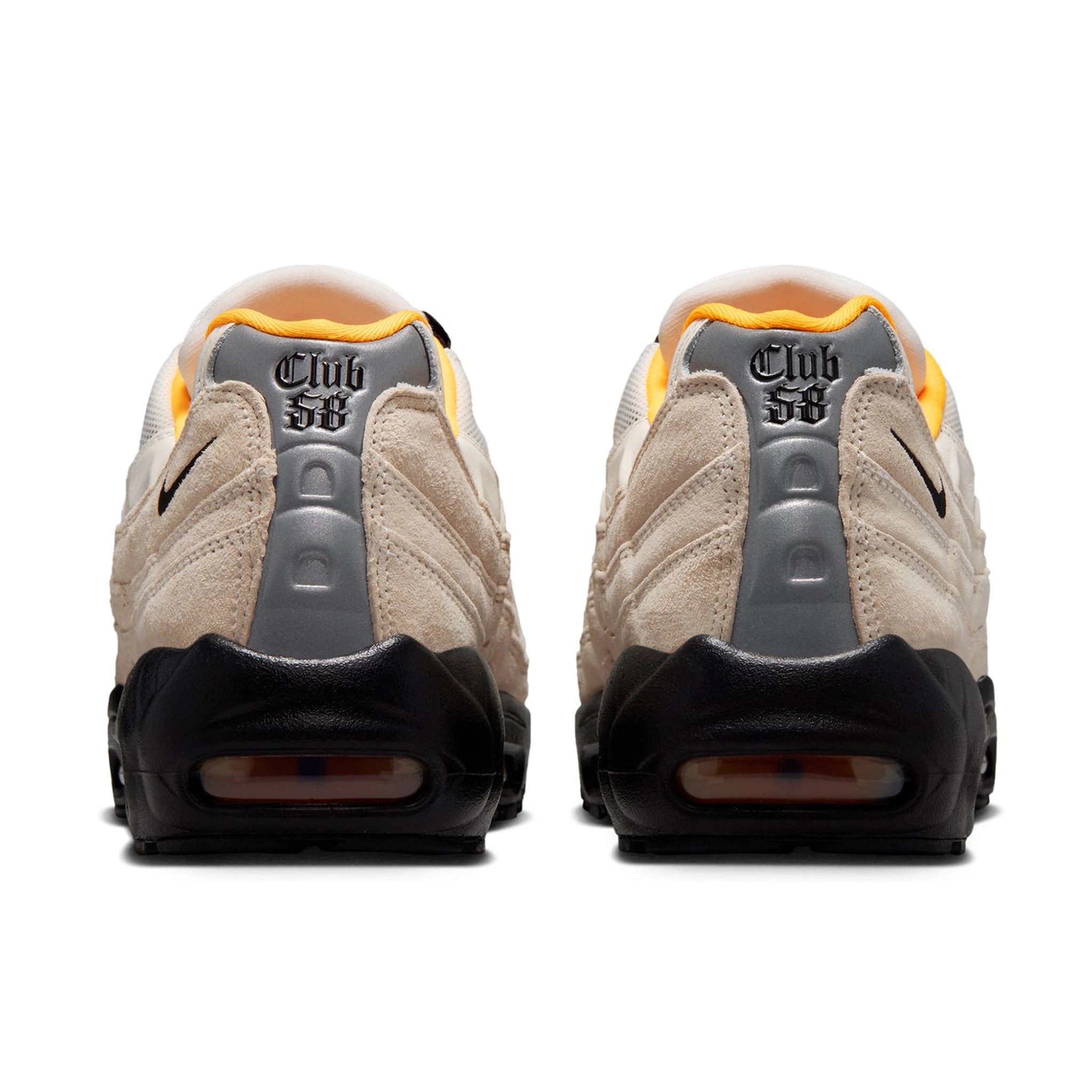 A pair of Sail white Nike SB 'Club 58' Air Max 95 skateboard sneakers with laser orange accents and black sole shown from the back on a white background