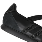 Close up of core black Adidas Originals Mary Jane sneaker with textured leather and suede panels, three rhinestone-embellished stripes, and a black elastic strap across the instep on a white background.