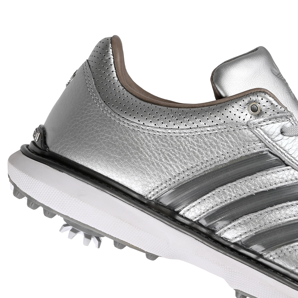 A close up of silver metallic Adidas x Metalwood MC70 golf shoe with gray stripes on a white background