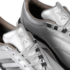 A close up of silver metallic Adidas x Metalwood MC70 golf shoe with gray stripes on a white background