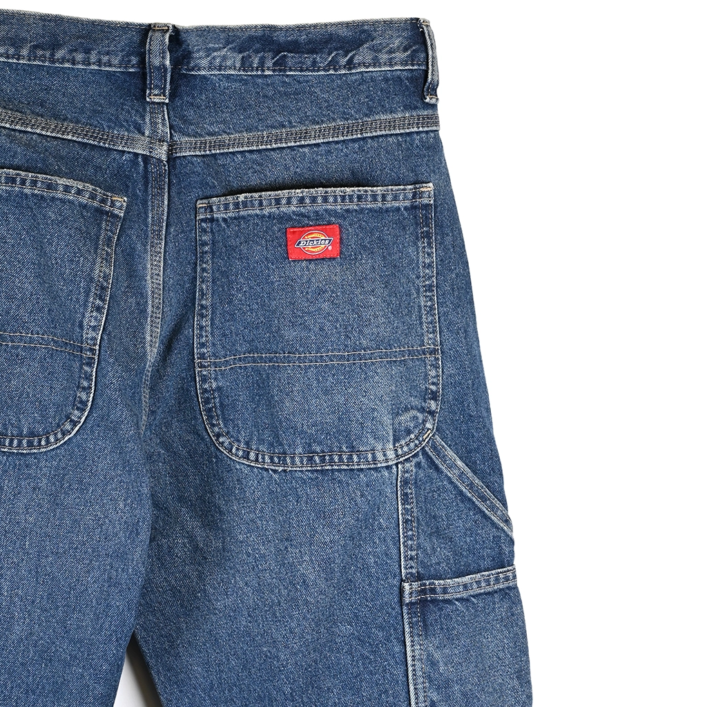 Close-up of Dickies blue denim pants with a red label on a white background