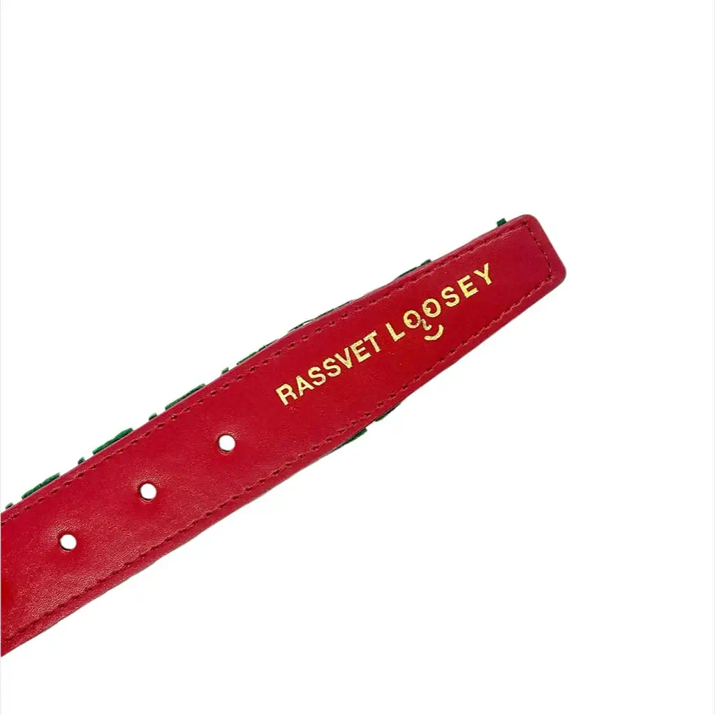 Close-up of Rassvet Loosey houndstooth belt showing red strap with gold branding and holes for adjustable fit.